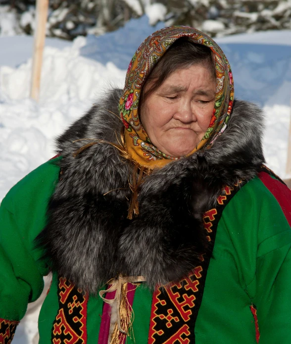 an older woman with a large hat standing in the snow