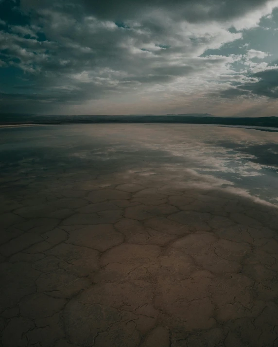 the sand and water has dark clouds in the background