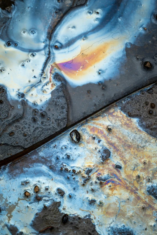 a metal plate with paint on it and a brown orange black and blue substance