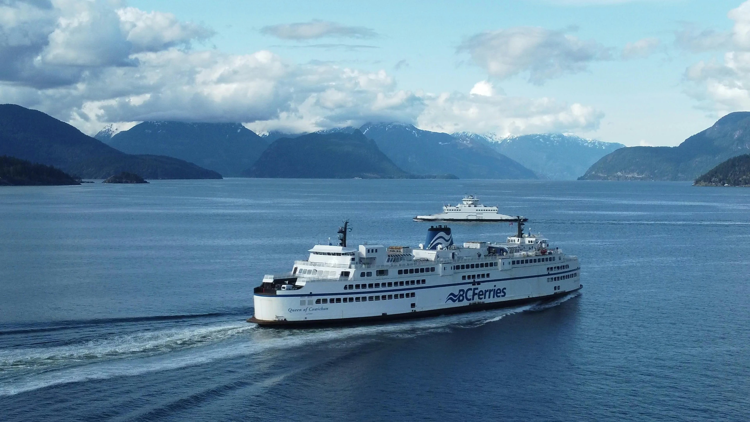 a ferry on a large body of water surrounded by mountains