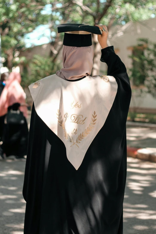 a woman dressed in black is holding a white and gold shawl