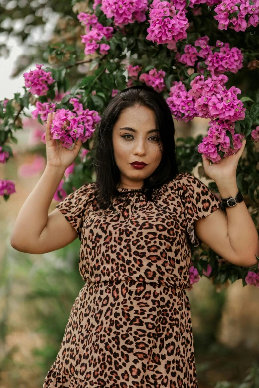 a woman standing in front of pink flowers