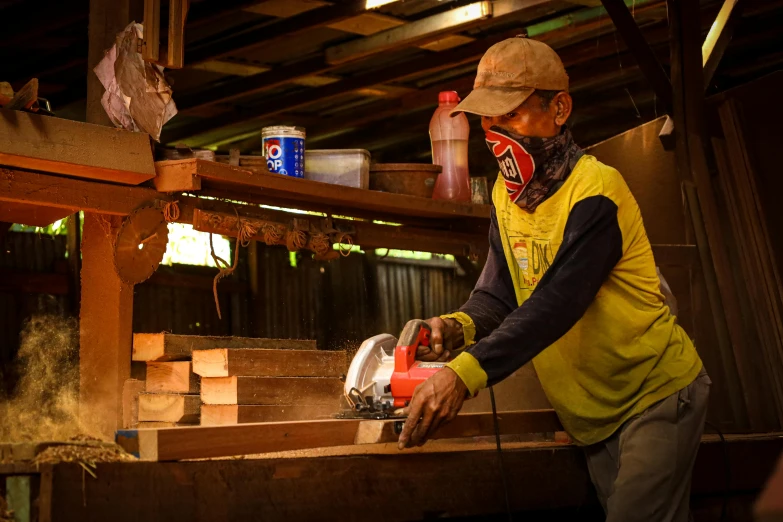 man in hat working with woodworking machine