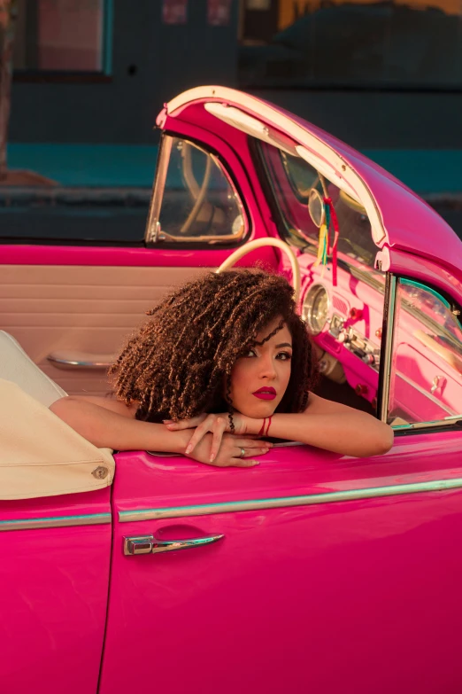a pretty young lady sitting in a pink car