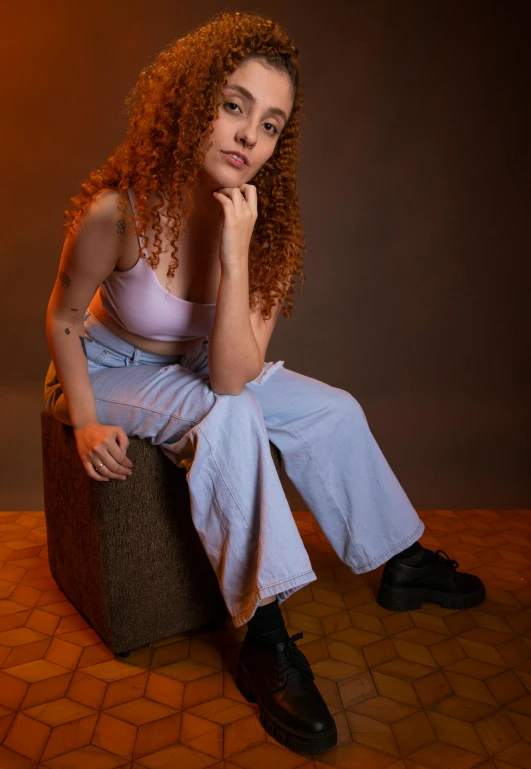 a woman with curly red hair sitting on top of a suitcase