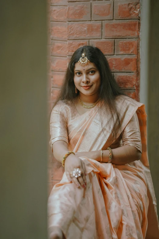 a beautiful woman in a white and orange sari sitting down