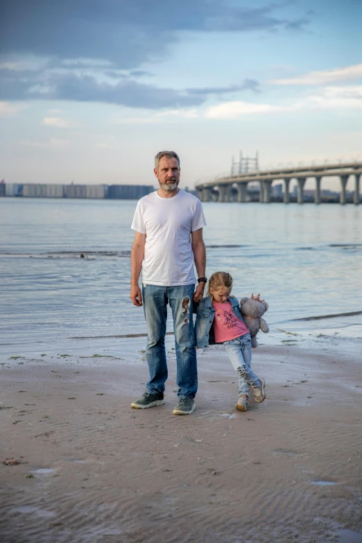 there is a man standing on the beach with a little girl