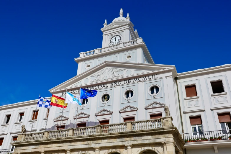 two flags fly on the balcony of an old building