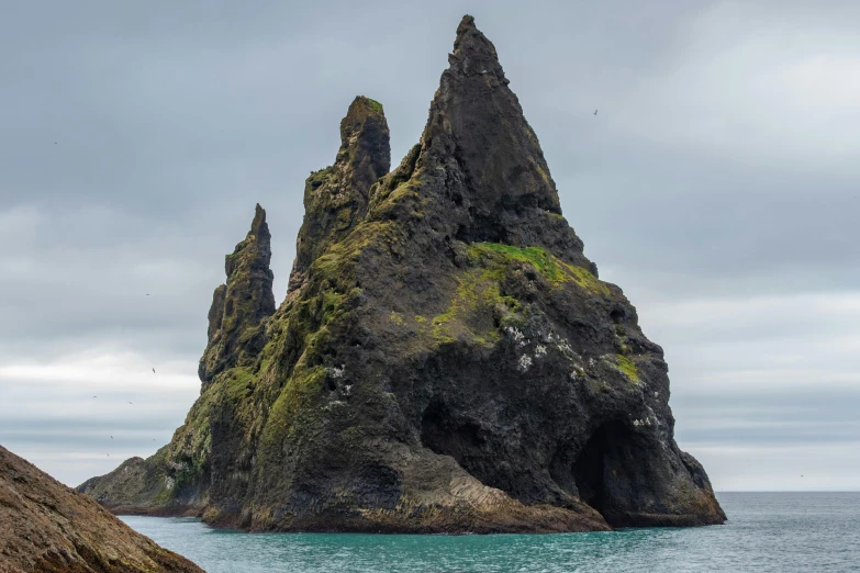 a large rock sticking out of the ocean next to rocks