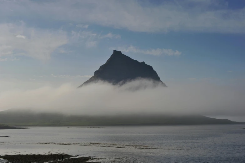 fog and low tide cover an island on a calm sea