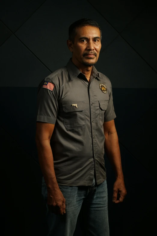 a man wearing a grey shirt and jeans standing