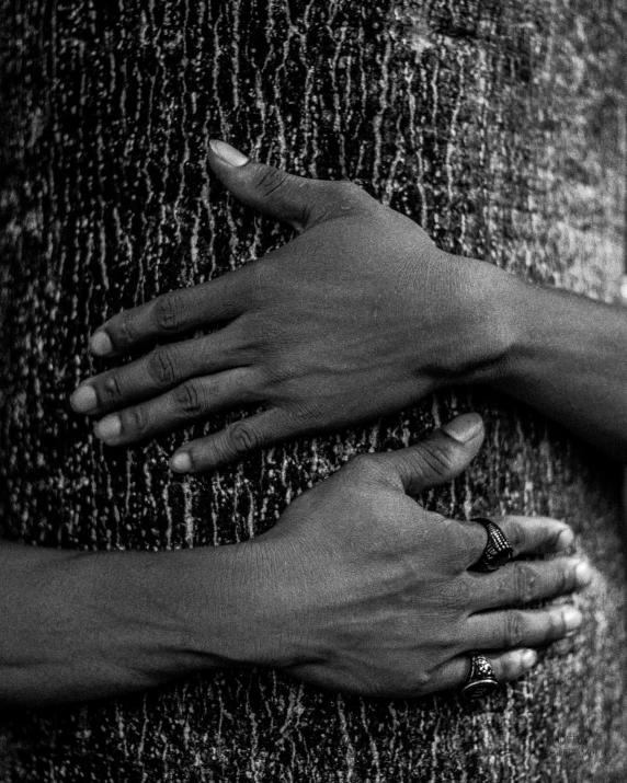 a person's hands hugging a tree with rain falling on it