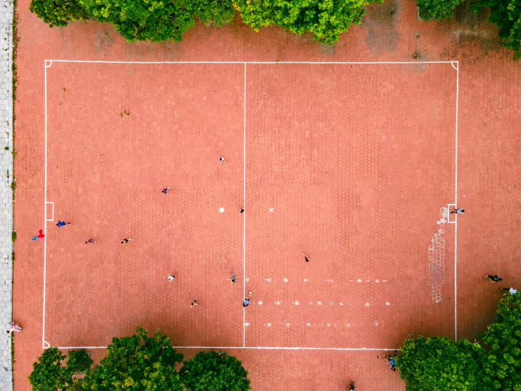 an overhead view of two tennis courts with trees around it