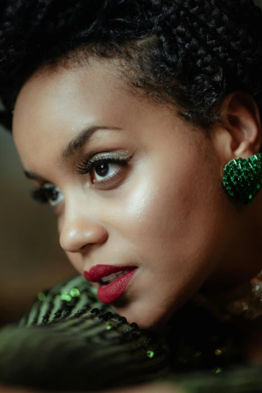 a young woman in green with a red lips looks up while wearing a red lipstick