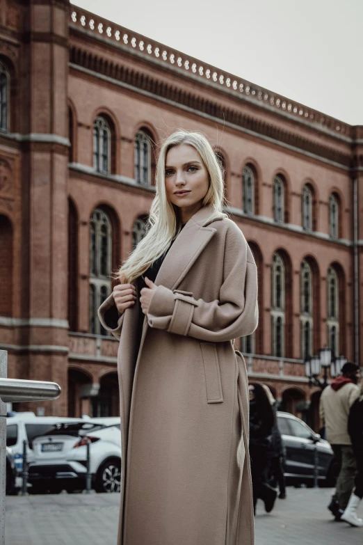 a woman in long coat standing on the sidewalk