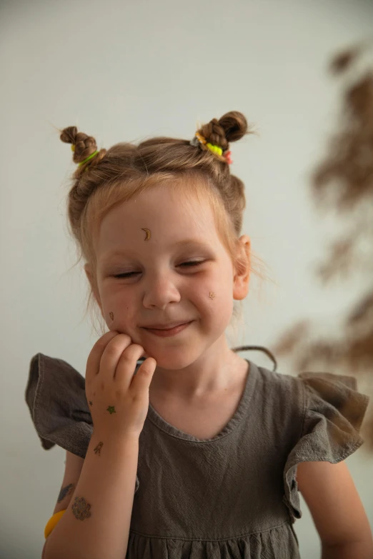 a little girl with her eyes closed with hair pinned in buns smiling