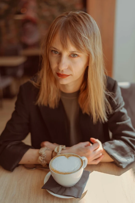 a woman sitting at a table with a cup of coffee in front of her