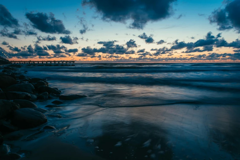 a beach at sunset with clouds and blue sky