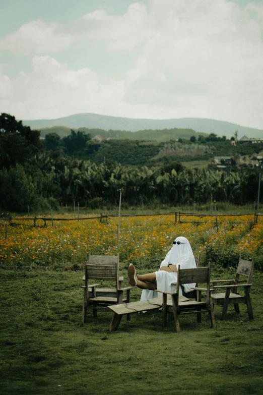 a man lays on a lawn with chairs and a camper