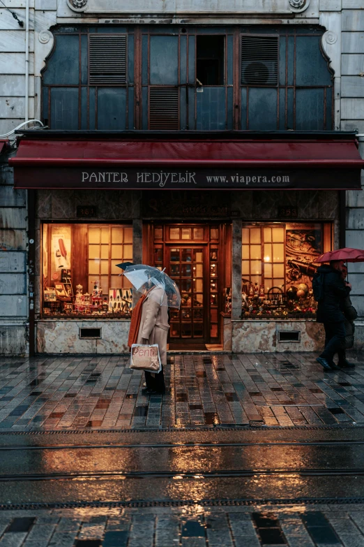 a person holding an umbrella walking down a sidewalk with other people in the rain