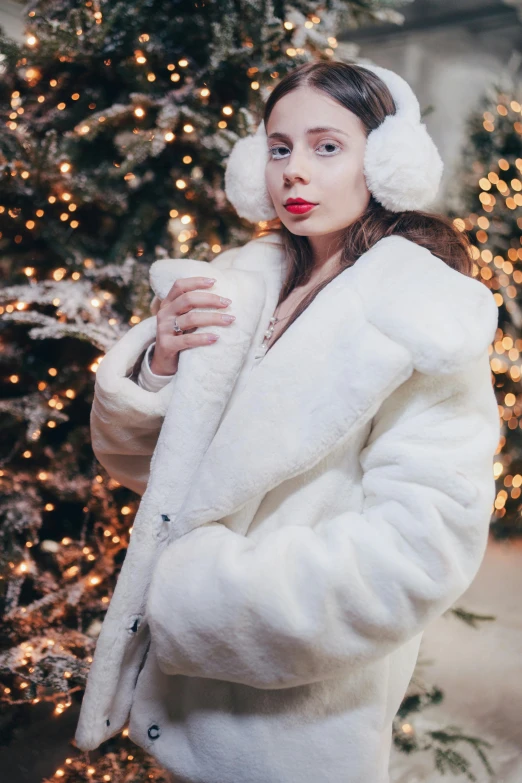 a person is posing in front of a christmas tree