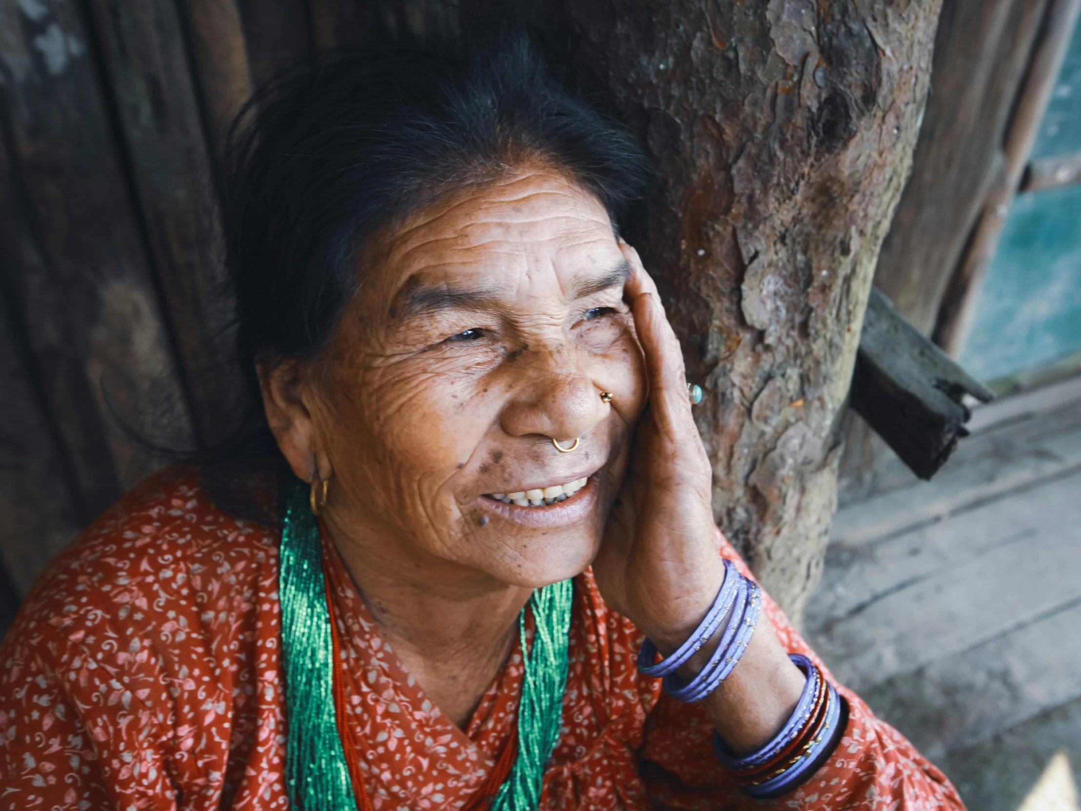 an older woman is smiling with a green necklace