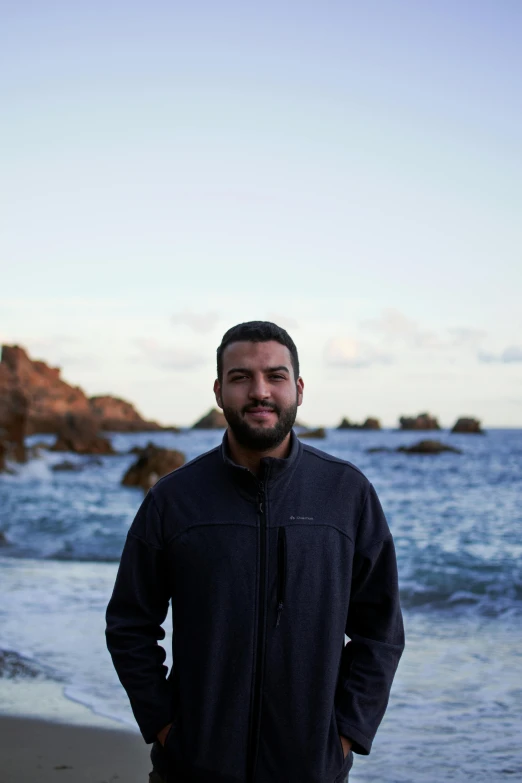 a man standing on top of a sandy beach next to the ocean