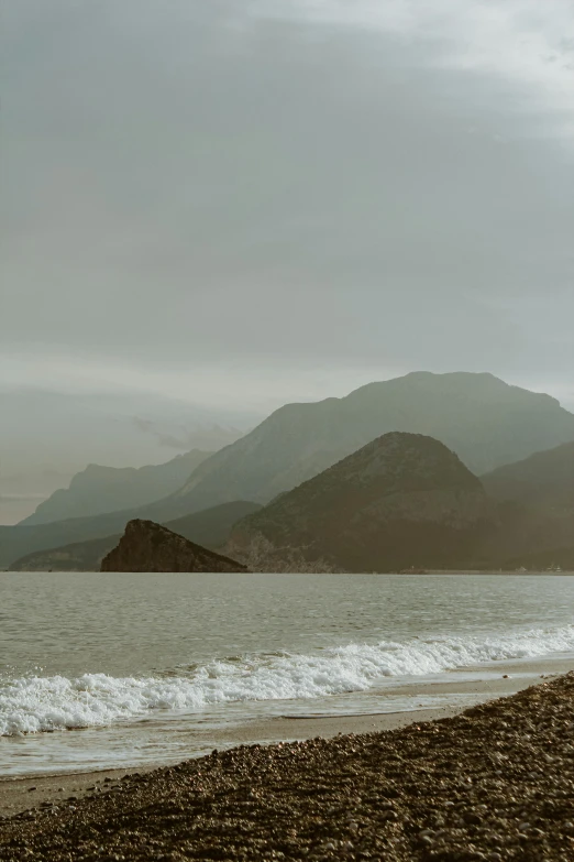 two people walk along the shoreline next to the water