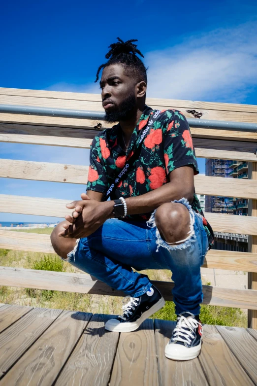 a man with dreadlocks sits on a wooden plank