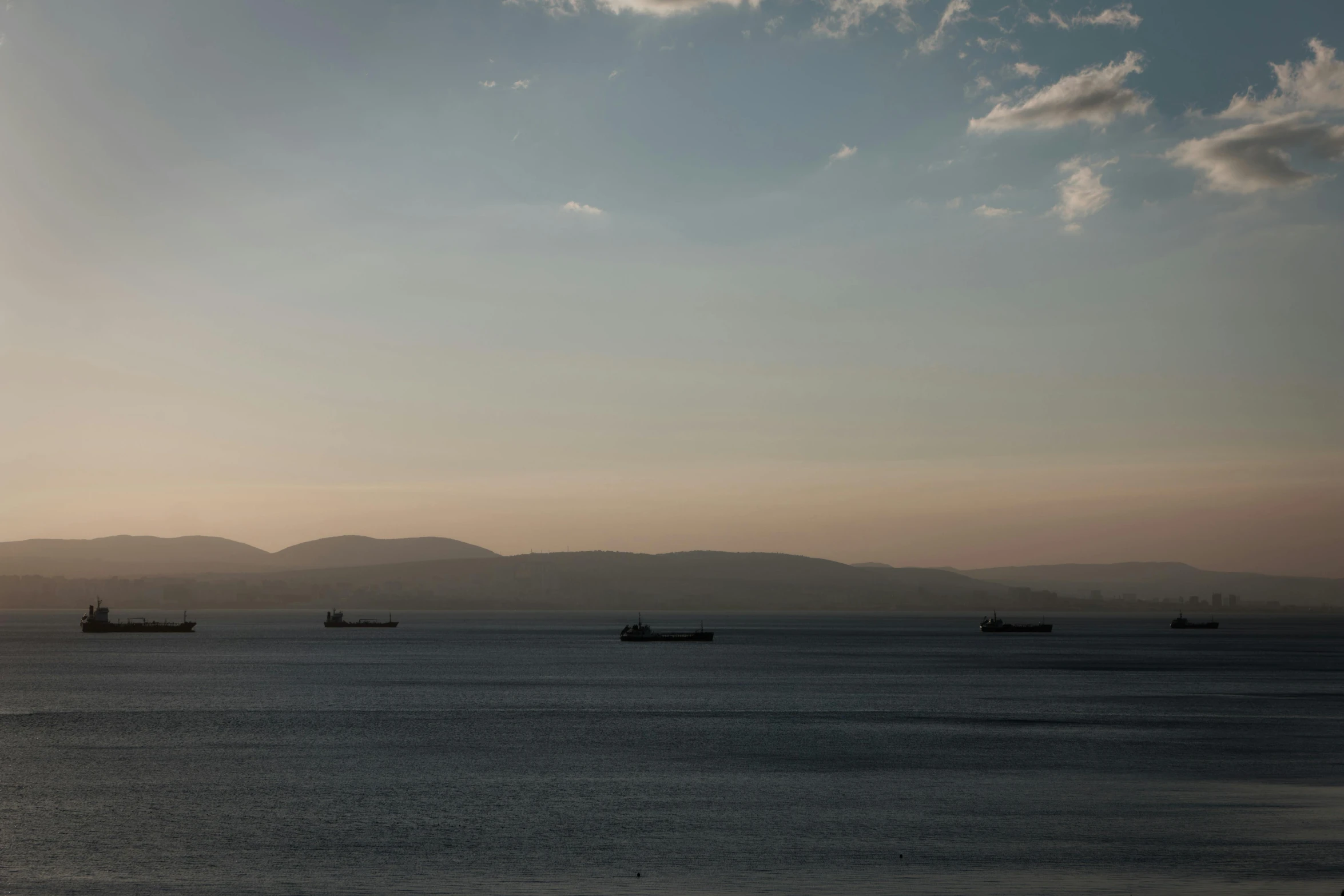 a group of boats out in the water at sunset