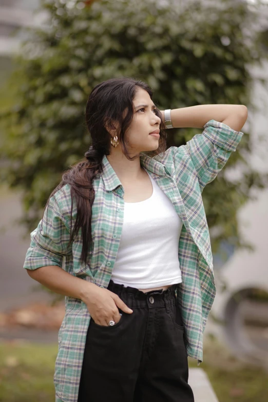 a woman looks into the distance while leaning against a tree