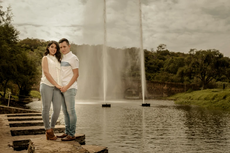 the couple stand near the water fountain in front of each other