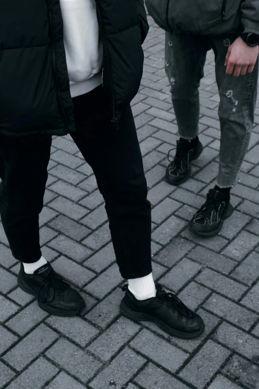 three people standing on a cobblestone street near a skateboard