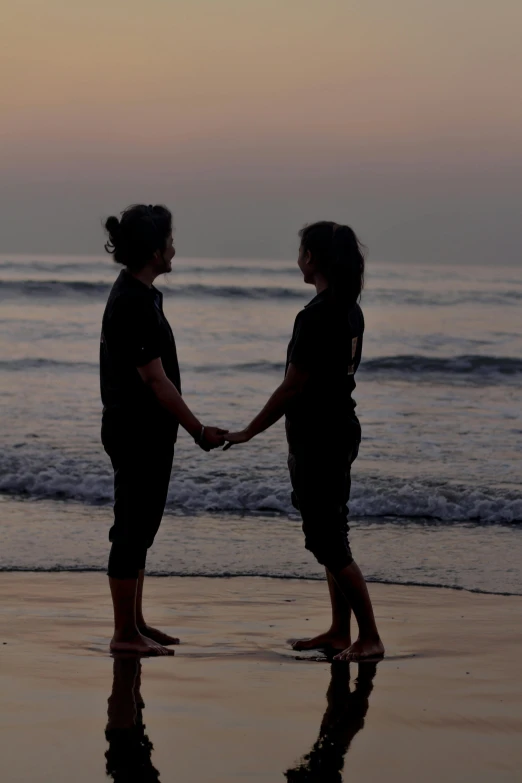 two women standing on the beach holding hands