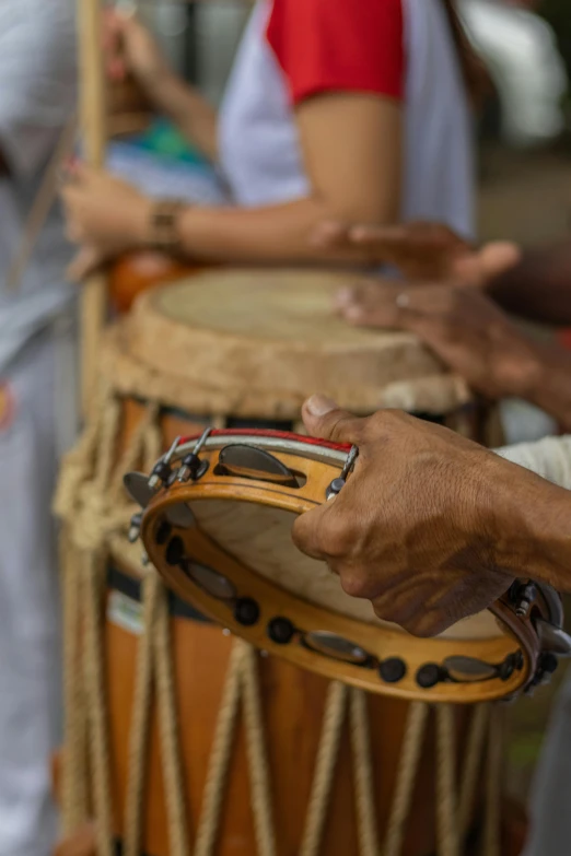 a hand holding drums with others behind them