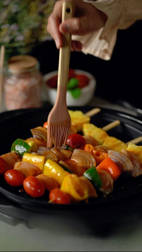 the person is holding a fork while sticking food into a tray