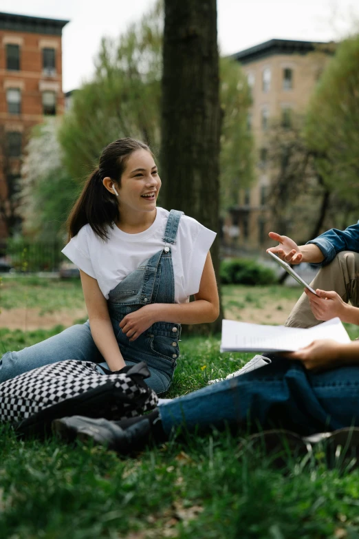 two students sitting on the grass laughing and discussing