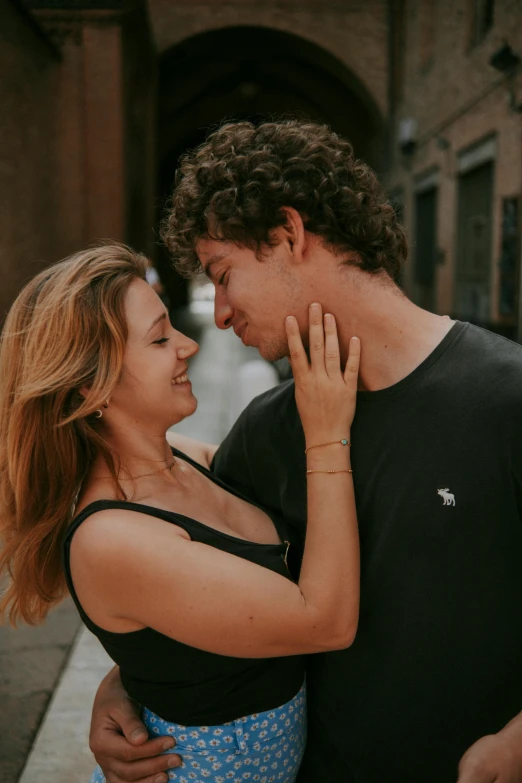 man hugging woman in black top and blue skirt on street