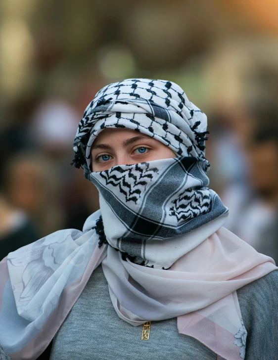 a woman wearing a black and white scarf and gray scarf with an interesting head piece