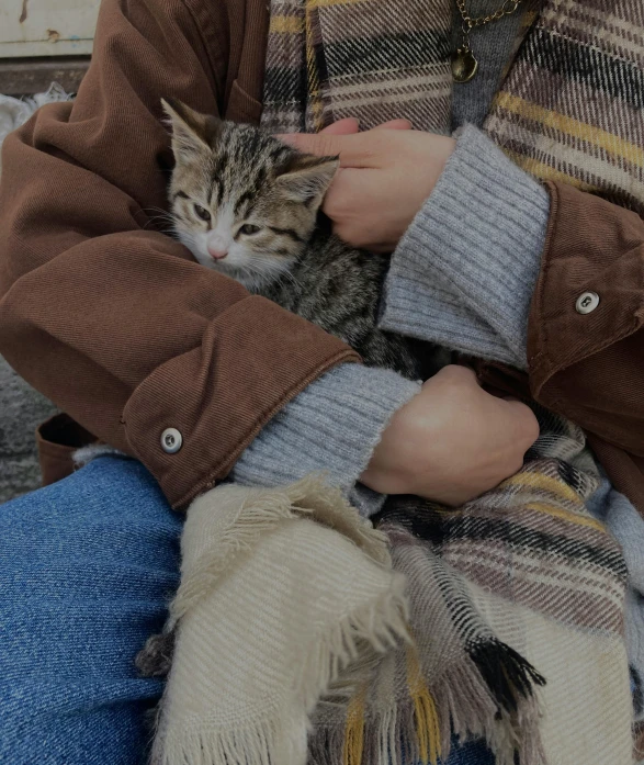 a woman sitting in front of her cat and holding it