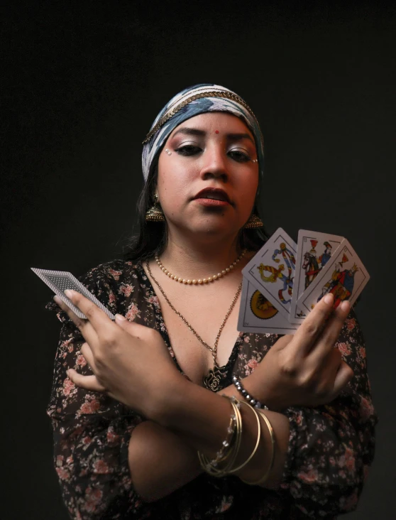 a woman in a headdress is holding a set of playing cards