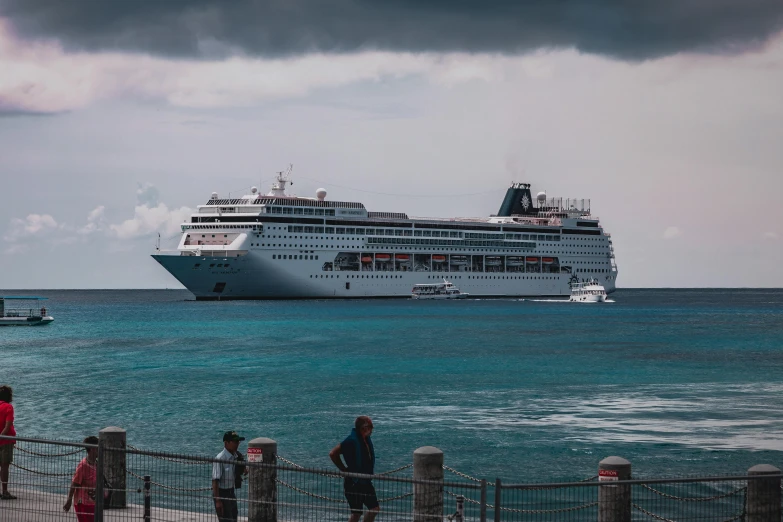 a cruise ship is in the water by a fence