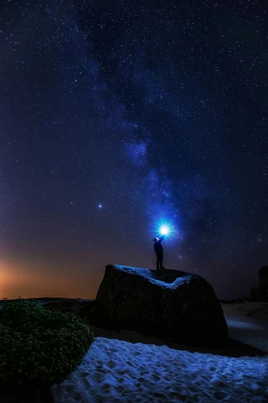 the sky is full of stars while a man stands on a rock