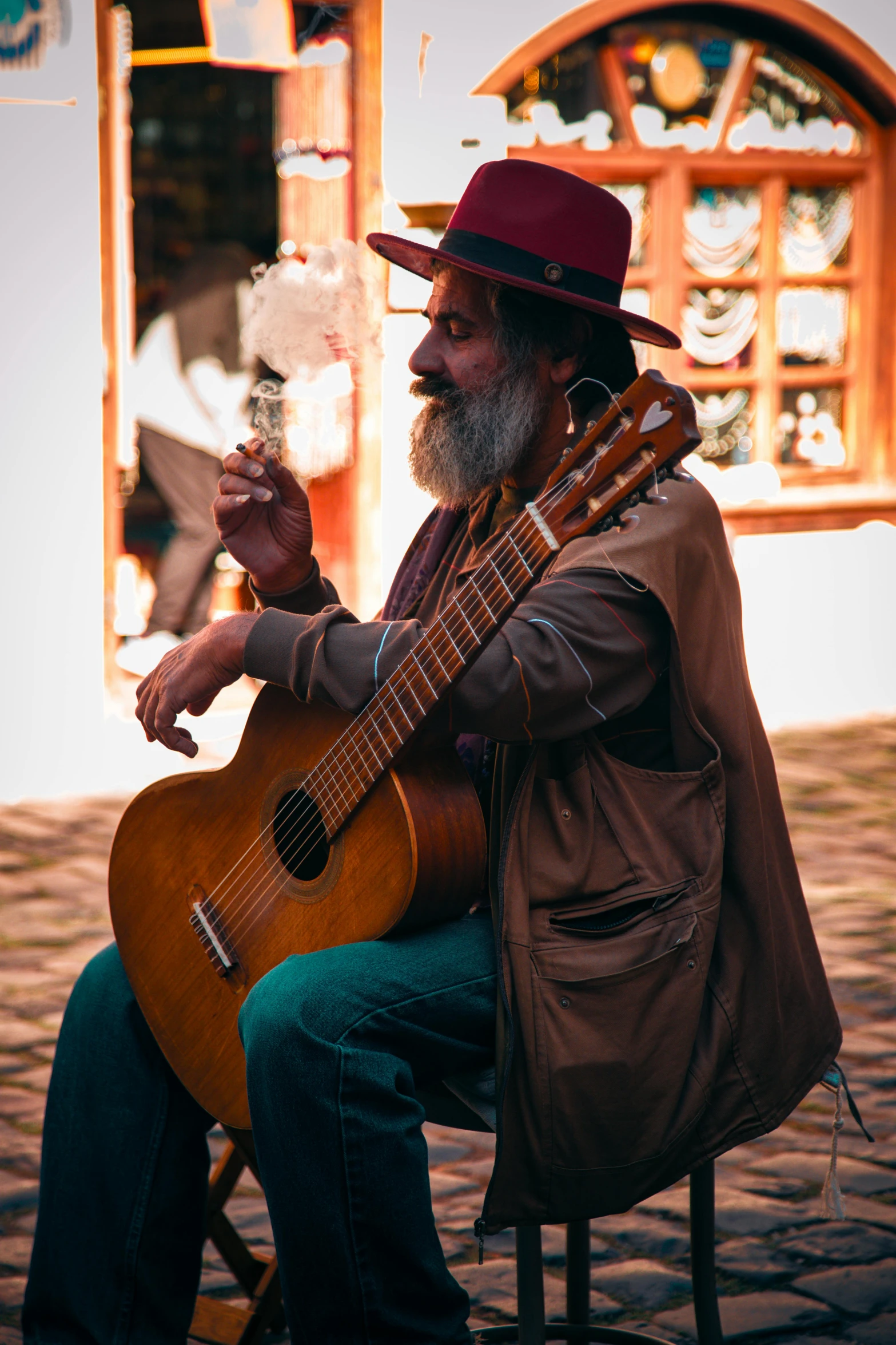 a man with a guitar and pipe sitting on a chair