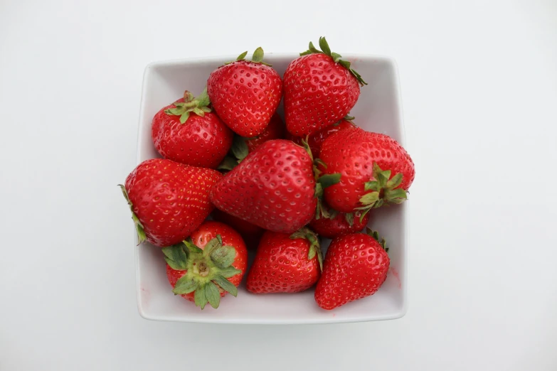 the fresh strawberries are placed in a white square bowl