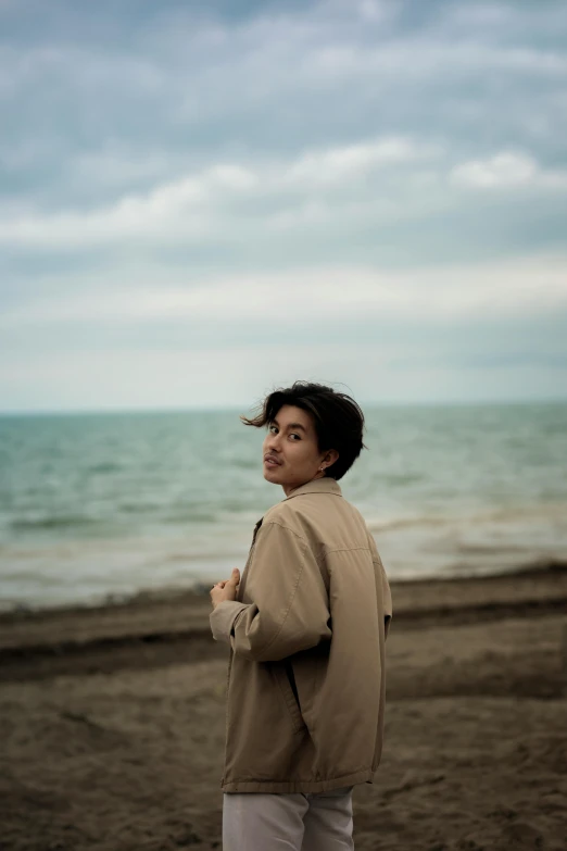 a woman standing on the beach with her hair flying in the wind