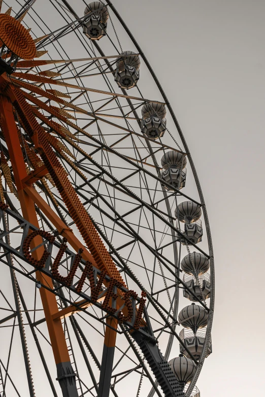 an orange ferris wheel sits on an overcast day