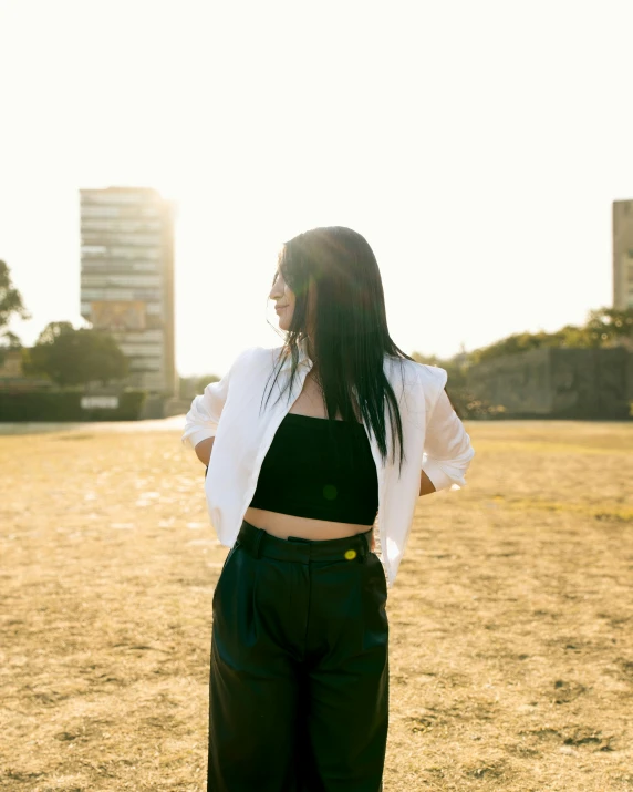 a young woman standing on a dry grass field