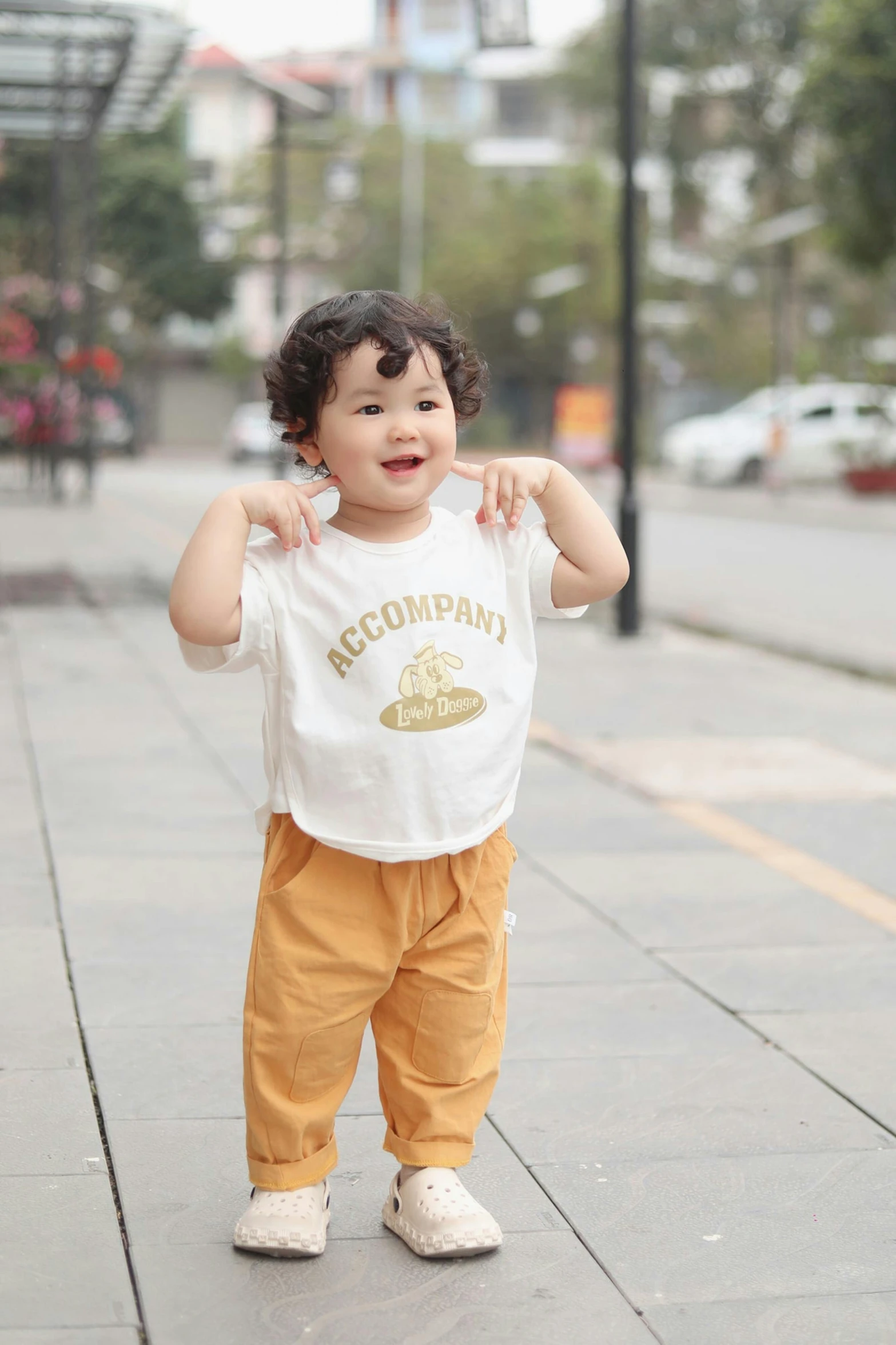 a small child on a sidewalk holding his hand up