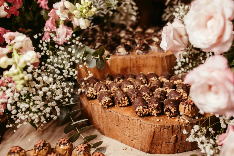 chocolate candies sitting on a wooden slab surrounded by flowers